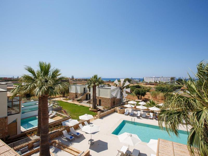 Nowoczesny obiekt z basenem, palmami i widokiem na morze pod czystym niebem.