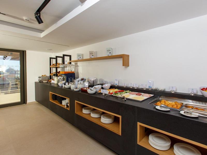 Strefa bufetu z różnorodnym jedzeniem i dostępem do tarasu w jasnym pomieszczeniu.