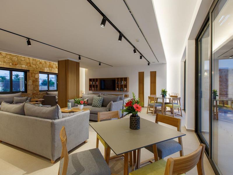 Nowocześnie urządzone salon i jadalnia z sofami, stołem i dużymi oknami.