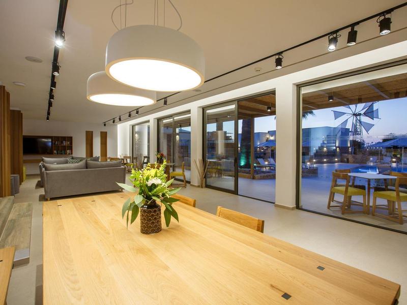 Nowoczesna jadalnia z dużym drewnianym stołem, kwiatami i widokiem na taras i basen.