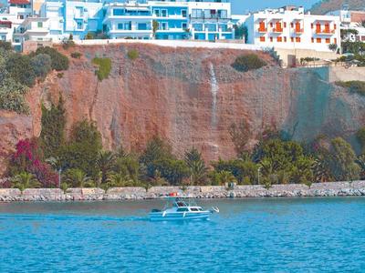 Hotel auf einer Klippe mit Blick auf das blaue Meer und ein Boot im Wasser.