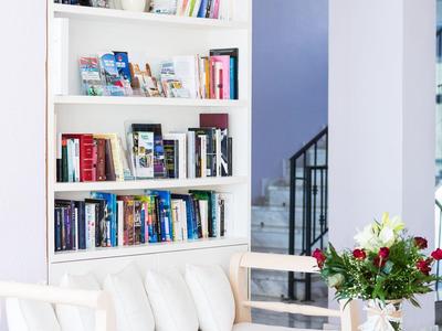 Heldere woonkamer met witte bank, boekenplank en tafel met bloemen.