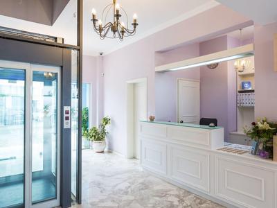 Lichte hotellobby met lift en witte receptiebalie.