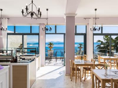 Helles Restaurant mit Blick auf das Meer und Tische mit Holzstühlen.