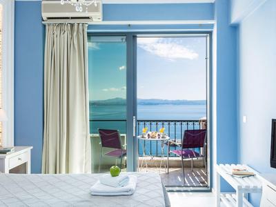 Lichte hotelkamer met zeezicht en balkon met tafel en stoelen.