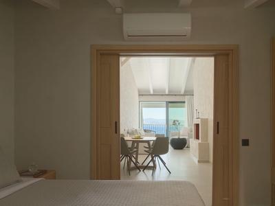 Blick von einem Schlafzimmer auf ein helles Wohnzimmer mit Meerblick.