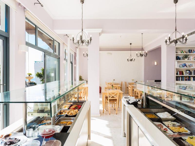 Licht café met glazen vitrines vol gebak en houten stoelen in eetgedeelte.