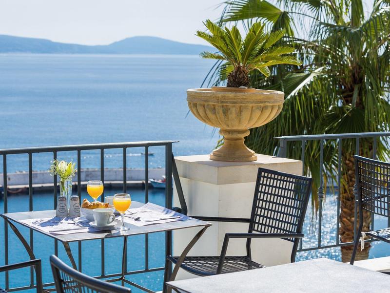 Tafel met ontbijt en uitzicht op zee met palmbomen op hotelterras.