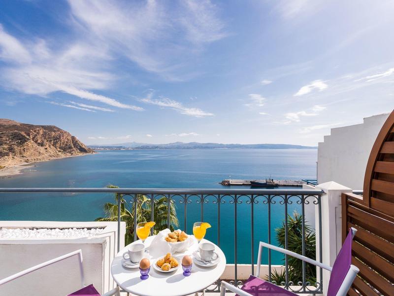 Terras met tafel en zeezicht op een zonnige dag met blauwe lucht.