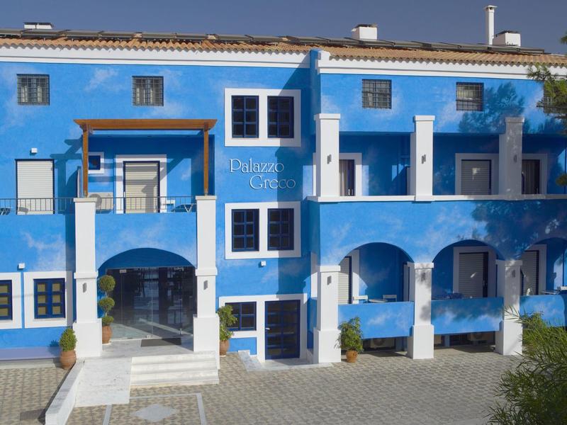 Blauw hotelgebouw met witte kozijnen en meerdere bogen bij de ingang.