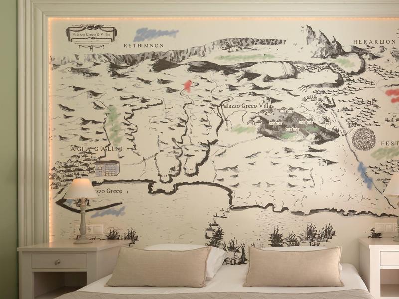 Slaapkamer met wereldkaart muurschildering, wit bed en nachtkastjes met lampen.