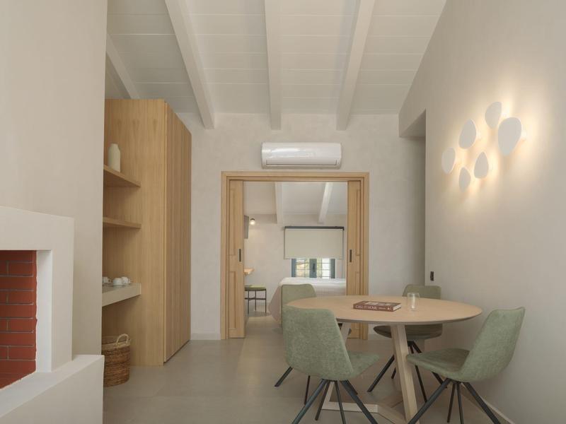 Moderne eethoek met ronde tafel en groene stoelen naast open haard en keuken.