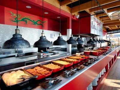 Buffet mit warmen Speisen und Brötchen in einem modernen Restaurant mit Holzdecke.