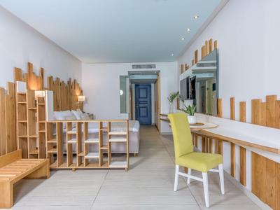 Nowoczesny pokój hotelowy z drewnianymi panelami ściennymi, żółtym krzesłem i biurkiem.