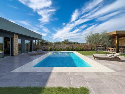 Moderner Pool mit blauem Wasser und Liegestühlen neben einem Haus und blühendem Garten.