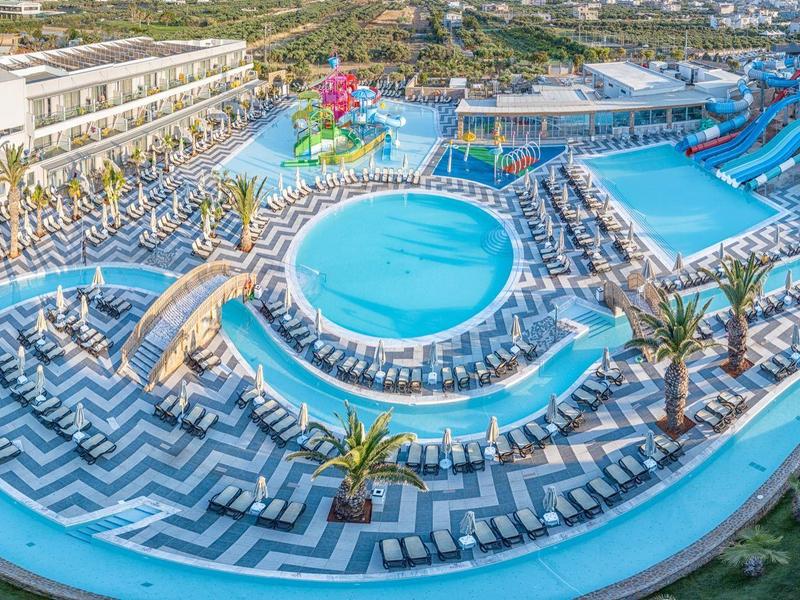 Large outdoor water park with multiple slides, pools, and lush green surroundings at a resort.