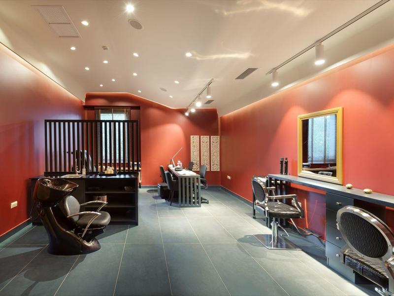Hotel salon with red walls, black chairs, and mirrors with ample lighting.