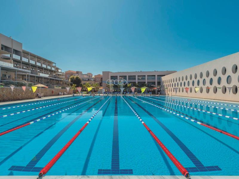 Large outdoor hotel pool with swimming lanes under clear sky.