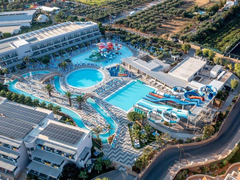 Aerial view of a large hotel resort with multiple swimming pools and water slides.