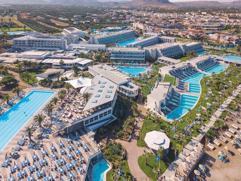 Aerial view of a large resort with multiple pools, sun loungers, and surrounding landscape.