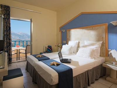 Camera d'hotel luminosa con letto matrimoniale, balcone e vista sul mare.