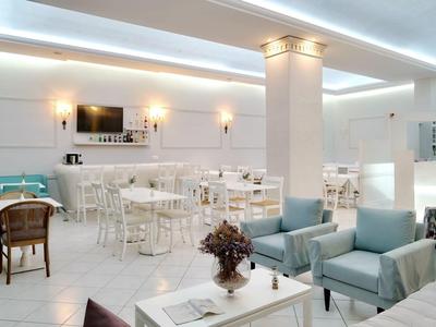 Area lounge moderna dell'hotel con mobili bianchi, gruppi di sedute e design minimalista.