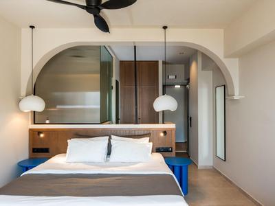 Camera moderna con letto matrimoniale, dettagli in legno e due lampade sospese sotto un arco.