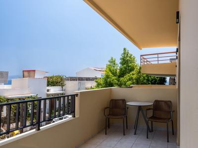Balcone con tavolo e due sedie con vista sugli edifici e alberi circostanti.
