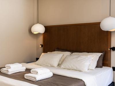 Camera d'hotel moderna con letto accogliente, asciugamani bianchi e lampade sospese.