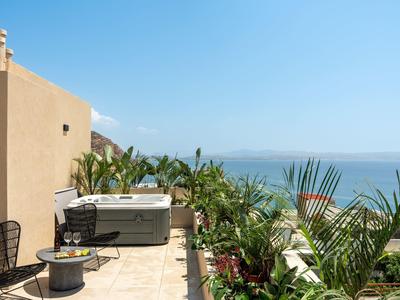 Terrazza con vasca idromassaggio, piante e vista mare sotto un cielo azzurro.