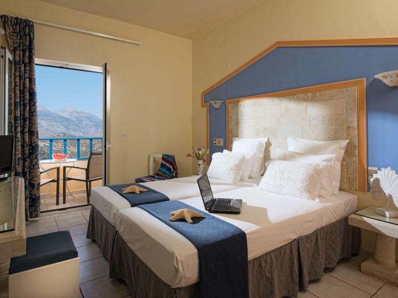 Camera d'hotel luminosa con letto matrimoniale, balcone e vista sul mare.