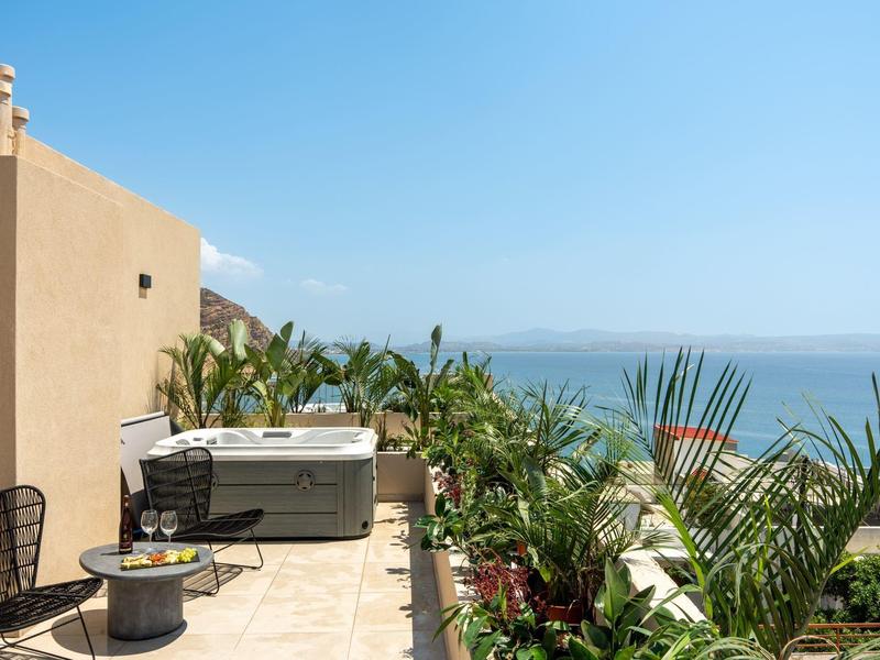 Terrazza con vasca idromassaggio, piante e vista mare sotto un cielo azzurro.