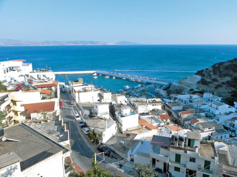 Nadmorskie miasto z białymi budynkami, portem i rozległym błękitnym morzem.