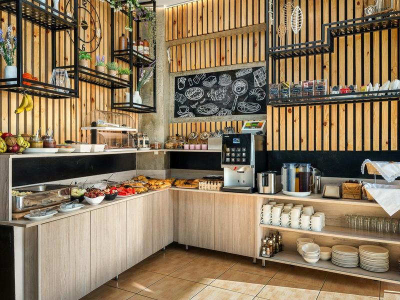 Nowoczesny kącik śniadaniowy z ekspresem do kawy i różnymi potrawami na drewnianych półkach.