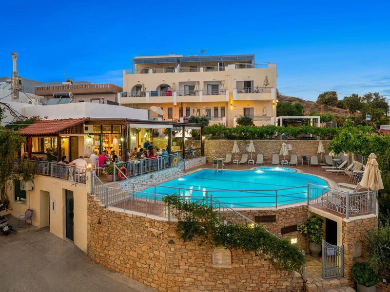 Hotel z okrągłym basenem i tarasem o zachodzie słońca, otoczony przyrodą.