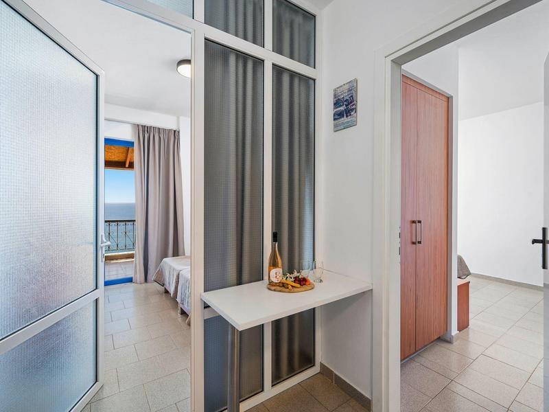 Widok z korytarza do jasnego pokoju z oknem i łóżkiem w hotelu.