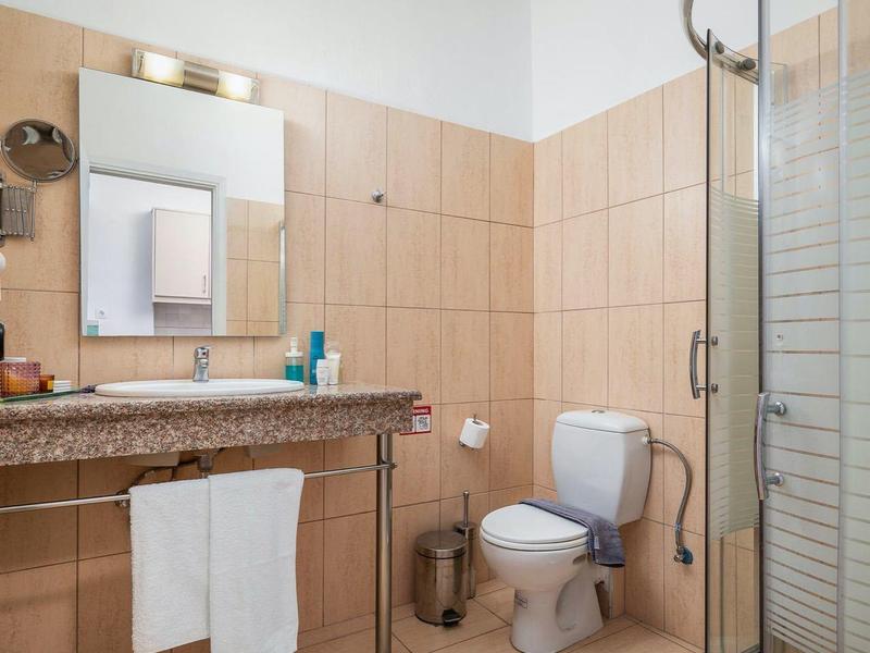 Nowoczesna łazienka z kabiną prysznicową, toaletą, umywalką i dużymi płytkami.