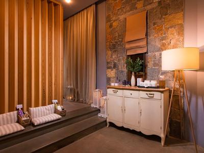 Przytulny pokój spa z dwoma stołami do masażu, ciepłym oświetleniem i dekoracją kamienno-drewnianą.