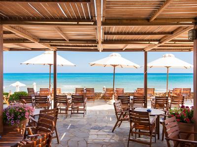 Otevřená terasa s stoly, židlemi a slunečníky s výhledem na moře