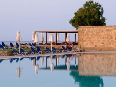 Klidná oblast u bazénu s modrými lehátky a kamennou zdí v pozadí