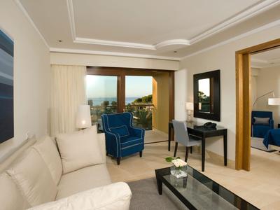 Habitación de hotel moderna con sofá, silla, escritorio y vista al balcón