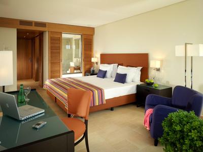 Habitación de hotel moderna con cama doble, escritorio, sillones y iluminación de hotel.