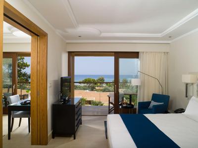 Chambre d'hôtel moderne avec grand lit et balcon donnant sur la mer.