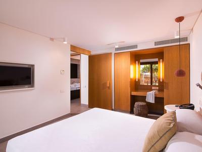 Chambre d'hôtel moderne avec lit double, téléviseur à écran plat et accents en bois chaleureux.