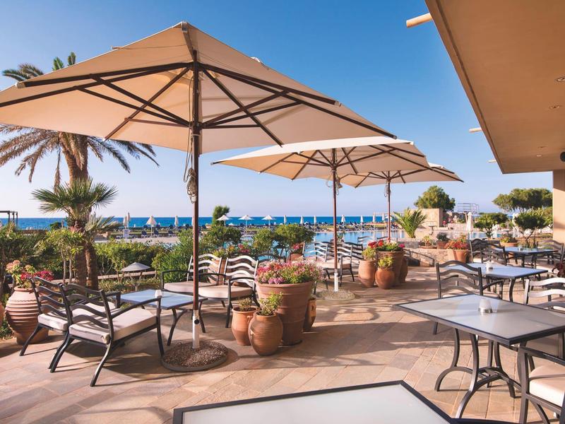 Taras hotelowy z parasolami i widokiem na morze pod bezchmurnym niebem.