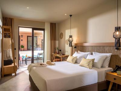 Moderner Hotelraum mit Doppelbett, Holzmöbeln, Balkon und weicher Beleuchtung.