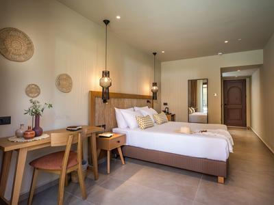 Helles Schlafzimmer mit Doppelbett, Holzmöbeln, Korbdekor an der Wand und modernem Lampenlicht.