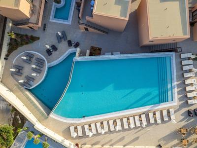 Ein großes, rechteckiges Schwimmbecken mit blauem Wasser, umgeben von weißen Liegestühlen.