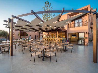 Moderner Außenbereich eines Cafés mit Stühlen, Tischen und Sonnenschutz, umgeben von Gebäuden.