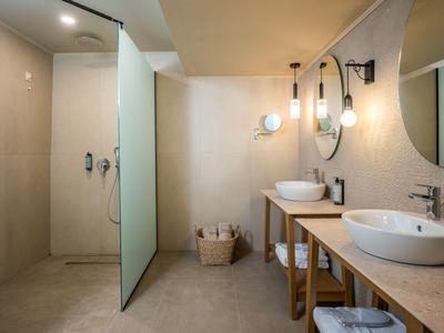 Modern bathroom with walk-in shower, two sinks, and minimalist design.